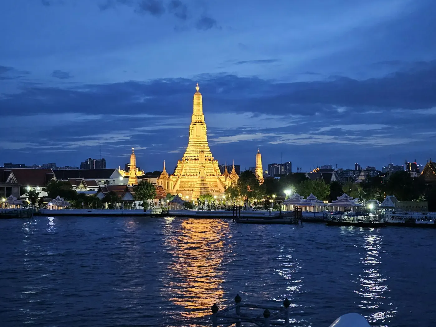 Wat Arun temple glowing at dusk over the Chao Phraya river, Bangkok